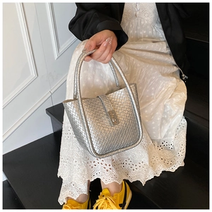 Silver woven bucket bag with metallic texture shown in a casual lifestyle setting