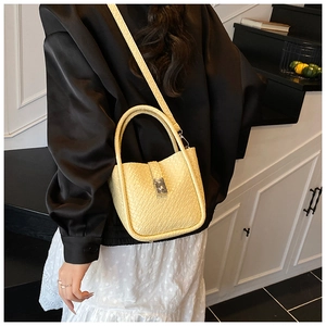 Close-up of a yellow bucket bag showing textured faux leather and a metal buckle detail