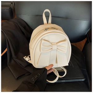 Detailed view of cream PU leather backpack featuring a large decorative bow and top handle