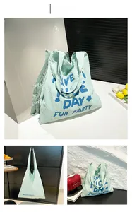 Détail du sac cabas en toile bleue à texture gaufrée avec motifs floraux et texte joyeux