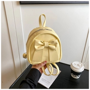 Close-up of cream yellow mini backpack featuring a large decorative bow and PU leather texture