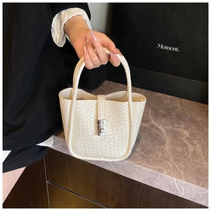 Detail of white woven bucket bag with leather texture and silver metal buckle closure
