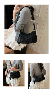 Detail of black crescent shoulder bag featuring ruched texture and metallic logo