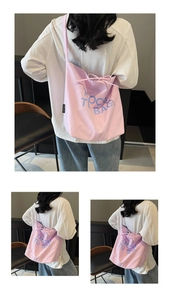 Detail of pink canvas tote bag showing the drawstring bow and blue letter printed logo