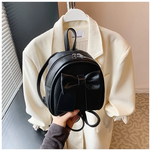 Detail of black faux leather mini backpack with a large bow and silver dual zippers