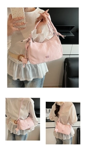 Close-up of pink pleated dumpling bag with metallic logo and decorative animal charm