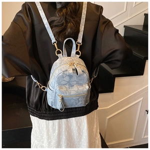 Détail d'un mini sac à dos en denim avec motif papillon et fermetures éclair dorées