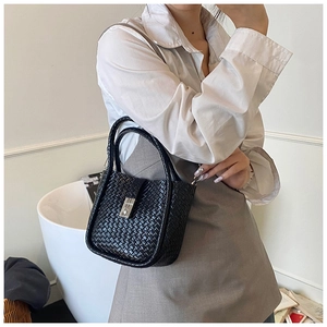 Close-up of black woven leather bucket bag featuring a silver metal lock and textured finish
