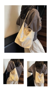 Detail of drawstring bow closure and blue checkered lining inside cream canvas tote bag