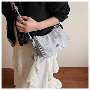 Silver wrinkled shoulder bag with metallic finish and logo detail on model outfit