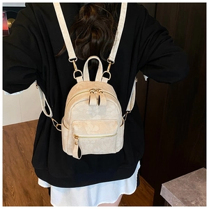 Mini cream backpack with embossed floral texture and gold hardware on female model back