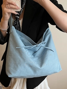 Minimalist light blue denim tote bag with rhinestone Good Luck text and bow tie design