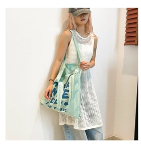 Détail du sac fourre-tout tissé vert menthe avec typographie florale bleue et grande capacité