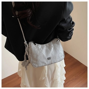 Détail du sac bandoulière plissé argenté avec charm éléphant et texture métallique