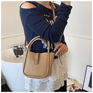 Detail view of woven bucket bag with silver metal swivel lock and adjustable shoulder strap
