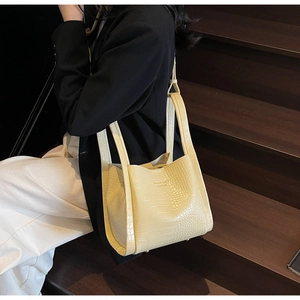 Mannequin avec un sac seau jaune à motif crocodile assis sur un escalier en bois