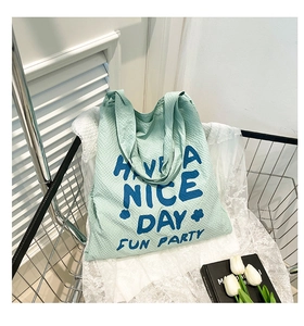 Détail du sac cabas en seersucker vert clair avec texte bleu et texture à carreaux