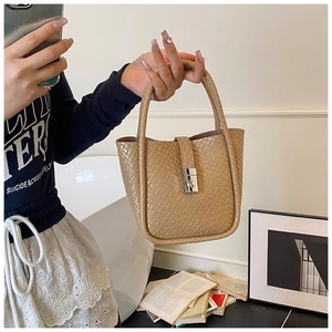 Close-up of beige crocodile pattern leather bucket bag with silver metal buckle detail