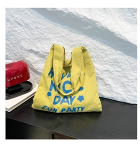 Détail du sac cabas en seersucker jaune avec slogan imprimé et texture en relief unique