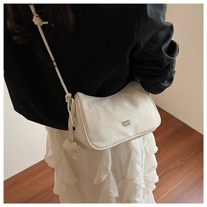 Vue latérale détaillée du sac demi-lune blanc texturé avec logo et breloque nuage