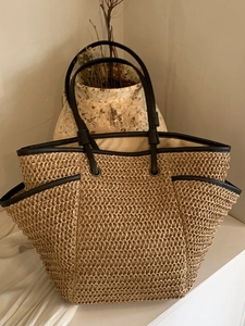 Large woven straw tote bag with black leather handles for beach and summer travel fashion