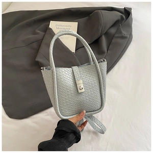 Detail shot of the light blue woven texture and silver metal twist lock on a bucket bag