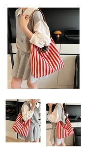 Detail view of large canvas tote bag featuring red and white stripes with brown leather handles