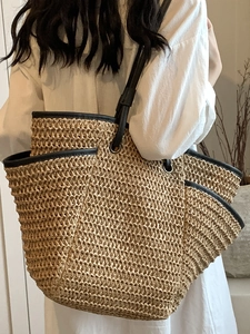 Minimalist straw tote bag with black leather straps shown on a model for beach style