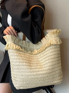 Große Strohtasche mit Fransen und braunen Lederriemen für den Sommerurlaub und Strand
