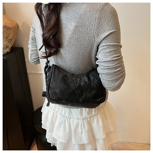 Gros plan du sac nuage noir plissé avec logo embossé et fine bandoulière élégante