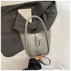 Detail of silver woven bucket bag with metallic texture on white bedding