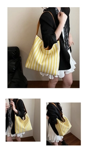 Detail of large canvas tote bag with yellow stripes and brown leather handles