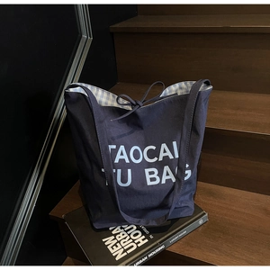 Detail of navy canvas tote bag featuring blue letter print and gingham lining with drawstring