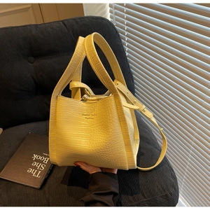 Détail de la texture crocodile jaune et du logo sur ce sac à main seau très élégant