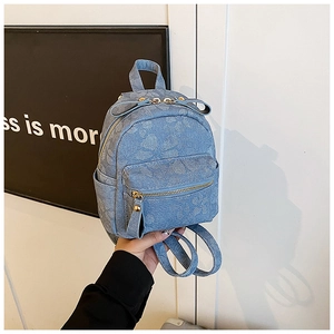 Détail d'un mini sac à dos en jean bleu clair avec gaufrage floral et zip doré