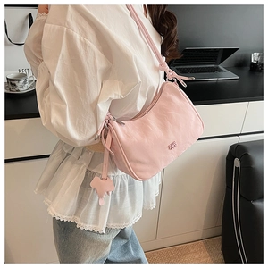 Pink pleated shoulder bag with cute pet charm shown in a professional office setting
