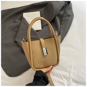 Close-up of khaki woven bucket bag with silver metal lock and textured leather details