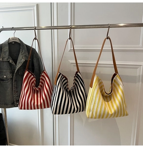 Detailed view of striped canvas tote bags in red, black, and yellow with leather straps