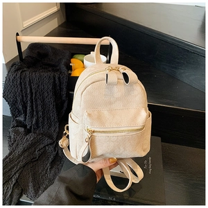 Détail d'un mini sac à dos blanc cassé minimaliste avec fermetures éclair dorées et texture