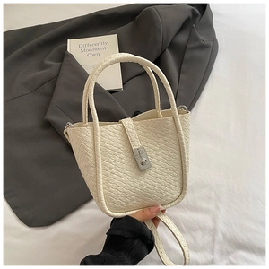 Detailed view of white bucket bag with litchi texture and silver metallic turn-lock