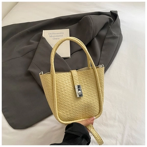 Detail shot of pale yellow woven bucket bag with silver twist lock and lychee texture