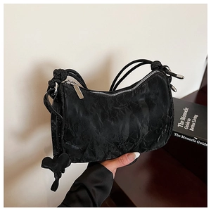 Détail du sac à bandoulière noir plissé avec fermeture éclair argentée et nœud sur la sangle