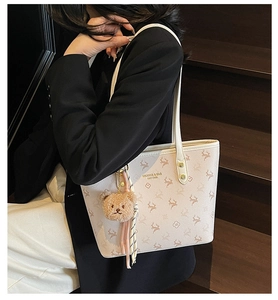 Detail view of large cream tote bag with deer pattern and brown plush bear charm