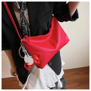 Detail view of red pebbled leather hobo bag with cute elephant charm on a model