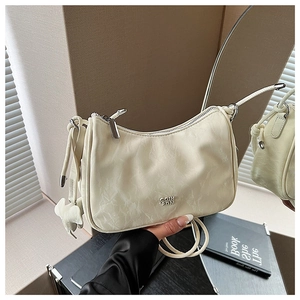 Gros plan du sac beige à texture plissée avec un charmant pendentif en cuir éléphant