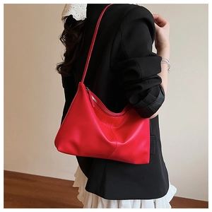 Red lychee textured leather underarm bag shown with black suit for elegant fashion look
