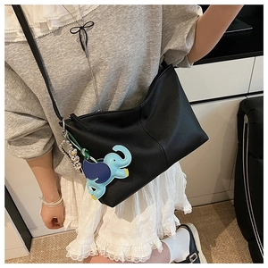 Detail of black litchi leather tote bag with blue elephant charm and silver metal chain