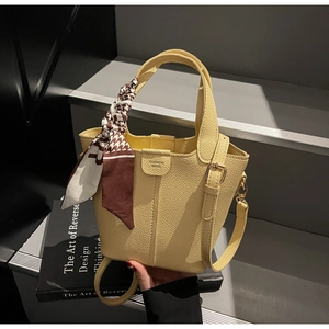 Dettaglio borsa a secchiello in pelle giallo chiaro con foulard in seta pied-de-poule