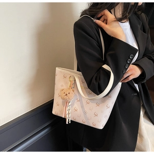 Detail of floral tote bag with deer pattern and cute plush bear charm accessory