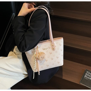 Detail of white leather tote bag featuring reindeer pattern and cute bear plush charm